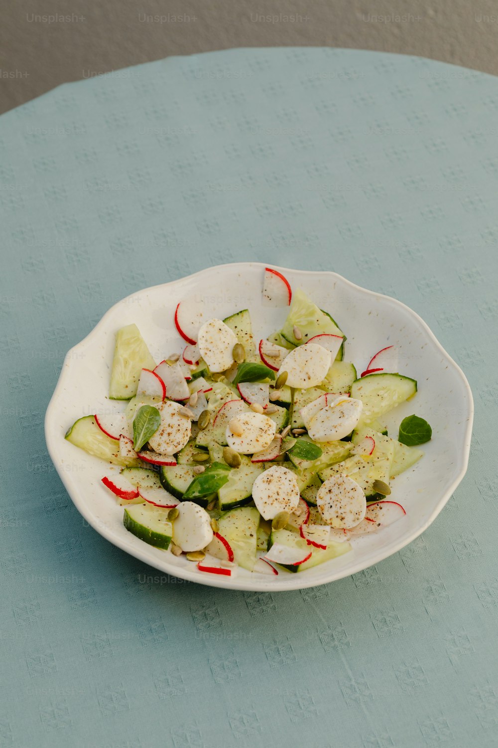 a white bowl filled with cucumbers and cheese
