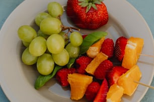 um prato branco coberto com uvas e laranjas