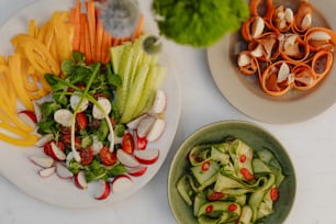 a white plate topped with lots of veggies next to a bowl of salad