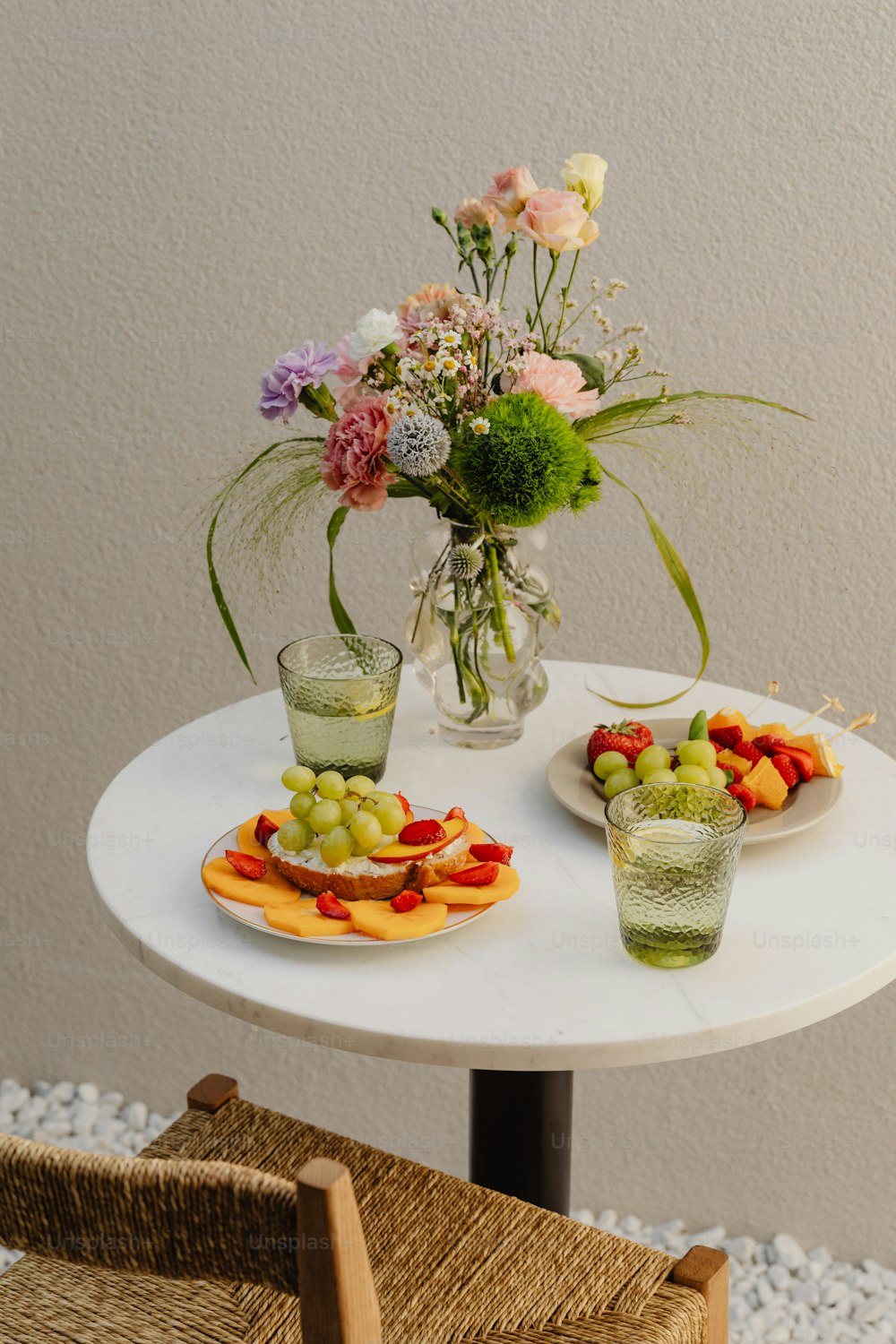 une table blanche surmontée d’assiettes de fruits et de fleurs