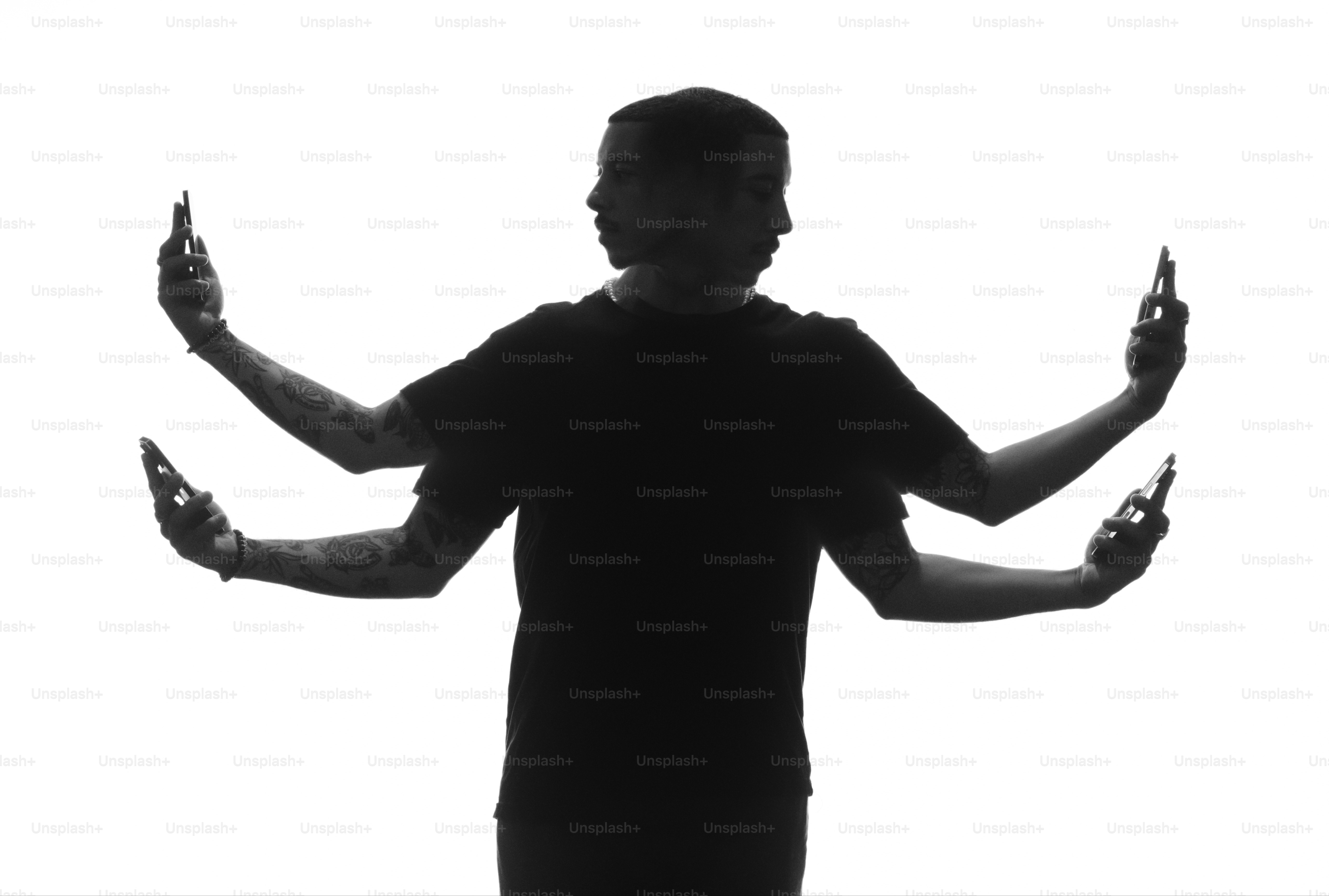 a man standing in front of a white background holding two cell phones