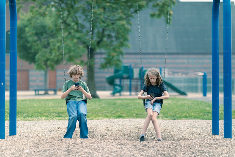 Dos niños jugando en columpios en un parque