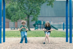 two children playing on swings in a park