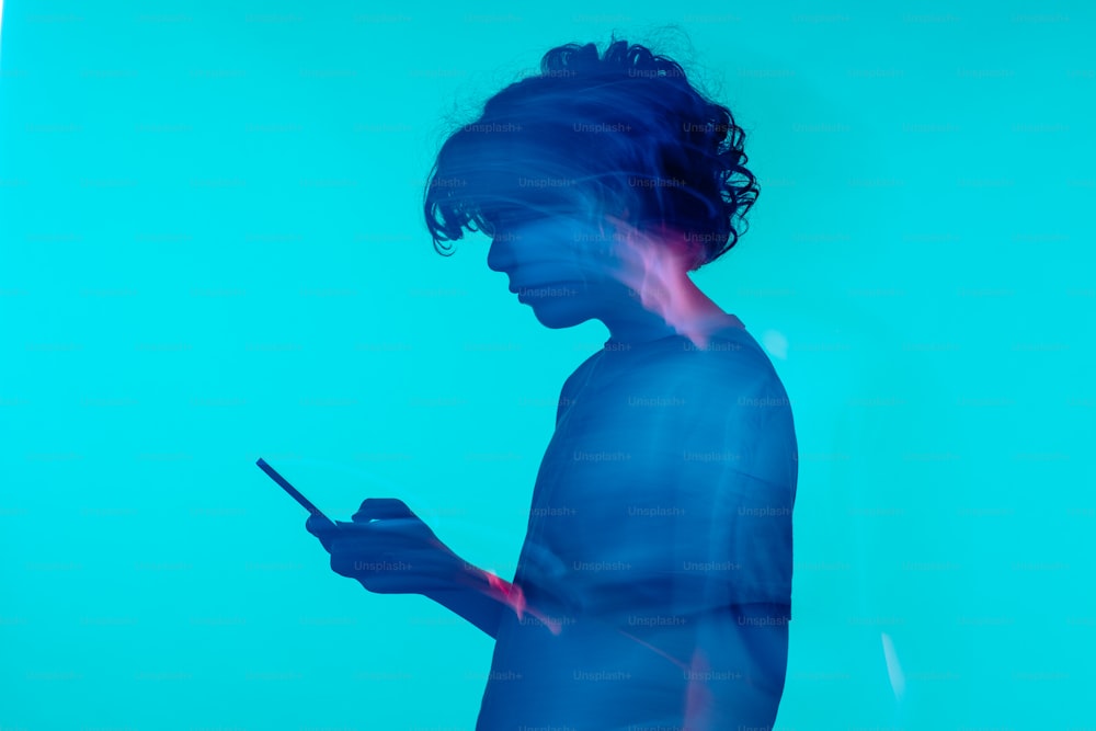 Un uomo in piedi davanti a un muro blu che usa un telefono cellulare