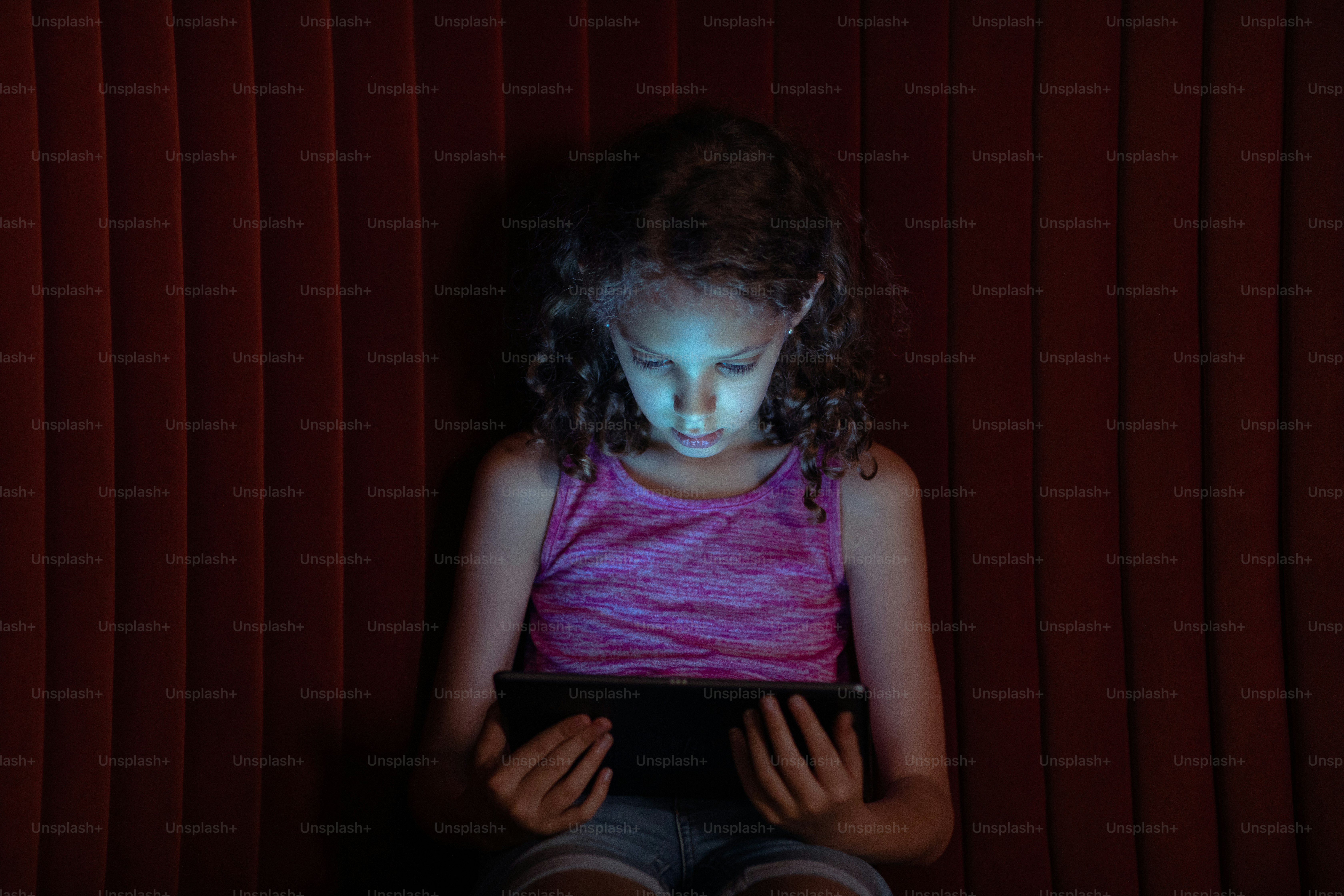 a little girl sitting in front of a tablet computer