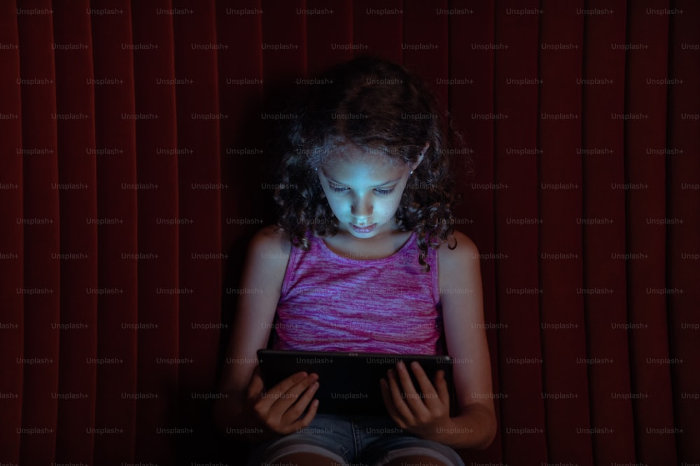 a little girl sitting in front of a tablet computer