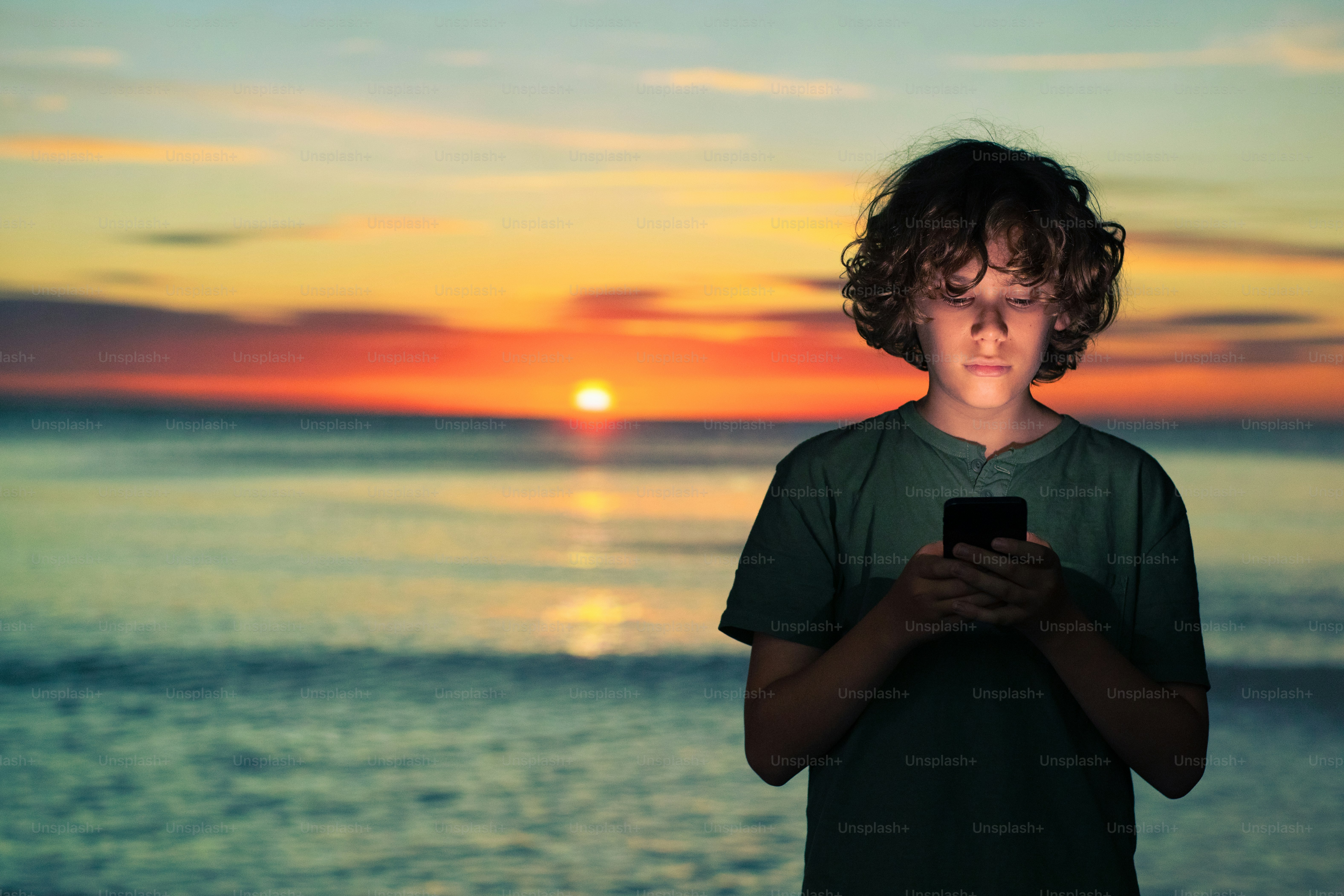 A man looking at his cell phone in front of a mountain photo ...