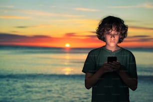 a young boy is looking at his cell phone