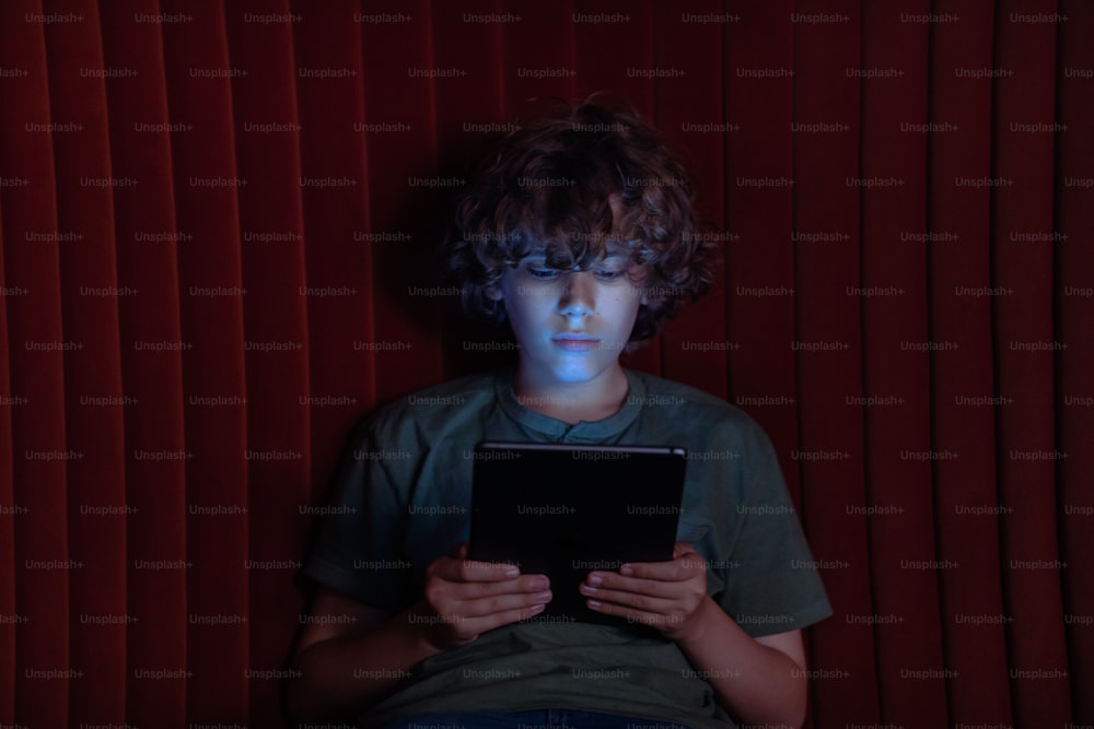 タブレットコンピュータの前に座ってい�る少年