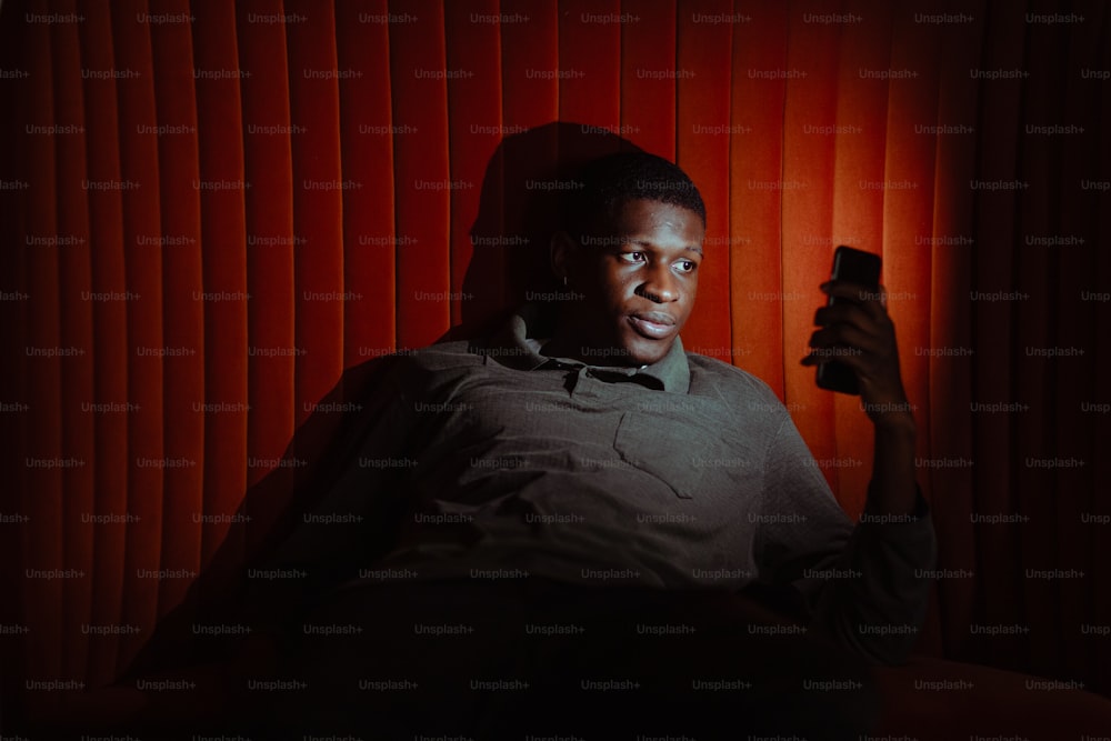 a man sitting in a chair holding a cell phone