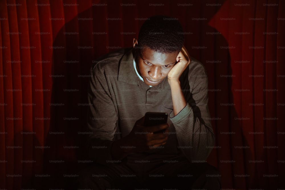 a man sitting in the dark looking at his cell phone