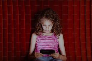 ein kleines Mädchen, das vor einem roten Vorhang sitzt