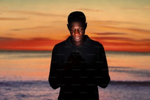 a man standing in front of a sunset using a cell phone