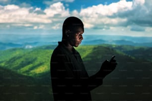 a man looking at his cell phone in the mountains