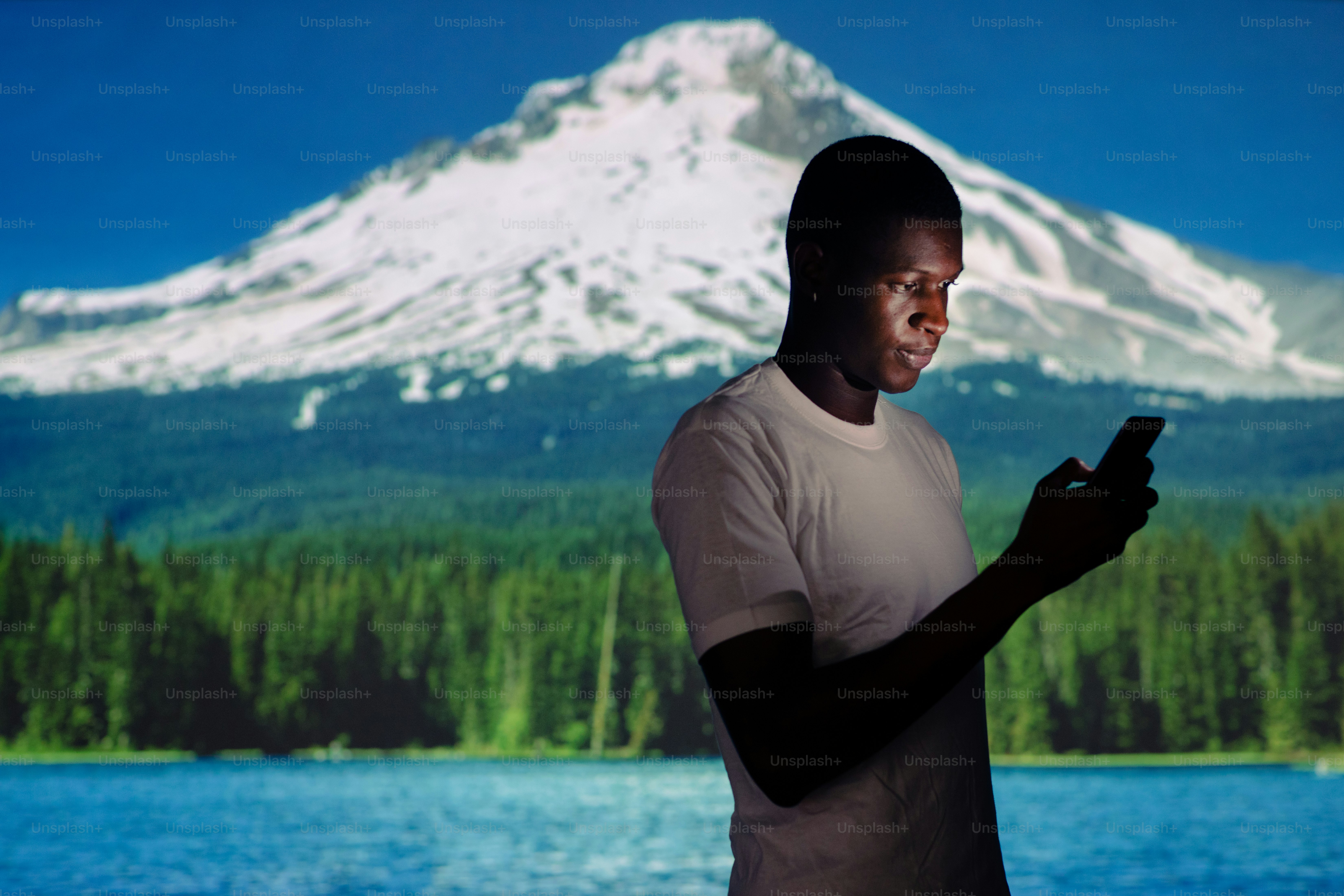a man looking at his cell phone in front of a mountain