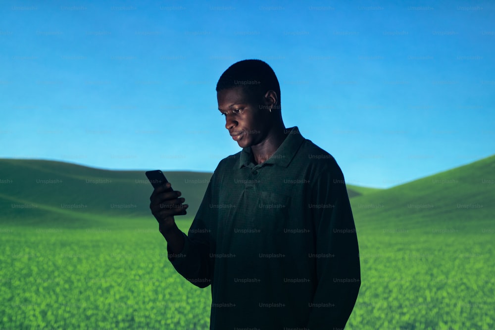 a man standing in a field looking at his cell phone