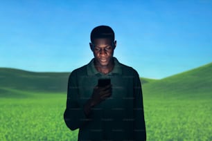 a man standing in a field looking at a cell phone