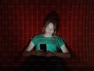 a woman sitting in a chair holding a cell phone