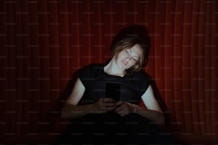 a woman sitting in a chair looking at a cell phone