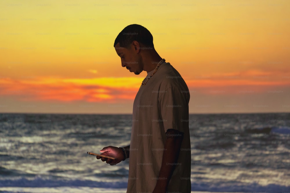 a man standing on a beach holding a cell phone