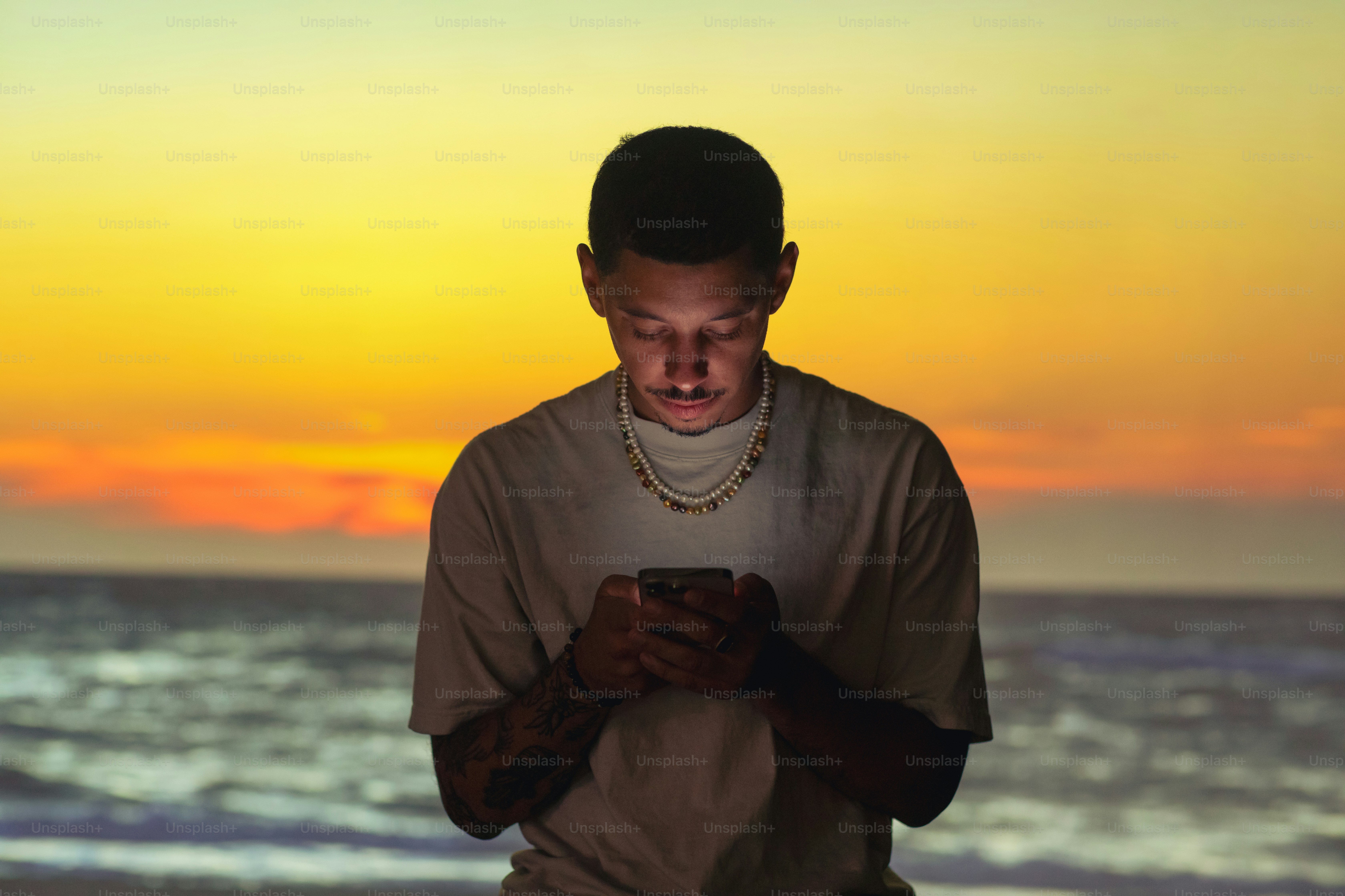 a man standing on a beach looking at a cell phone
