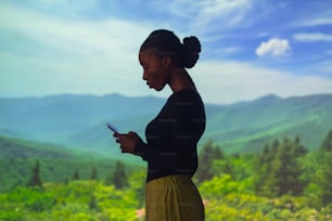 a woman looking at her cell phone in the mountains