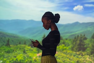 a woman standing in a field looking at her cell phone