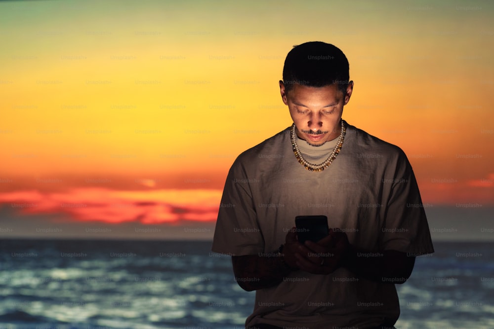 a man standing in front of a sunset using a cell phone