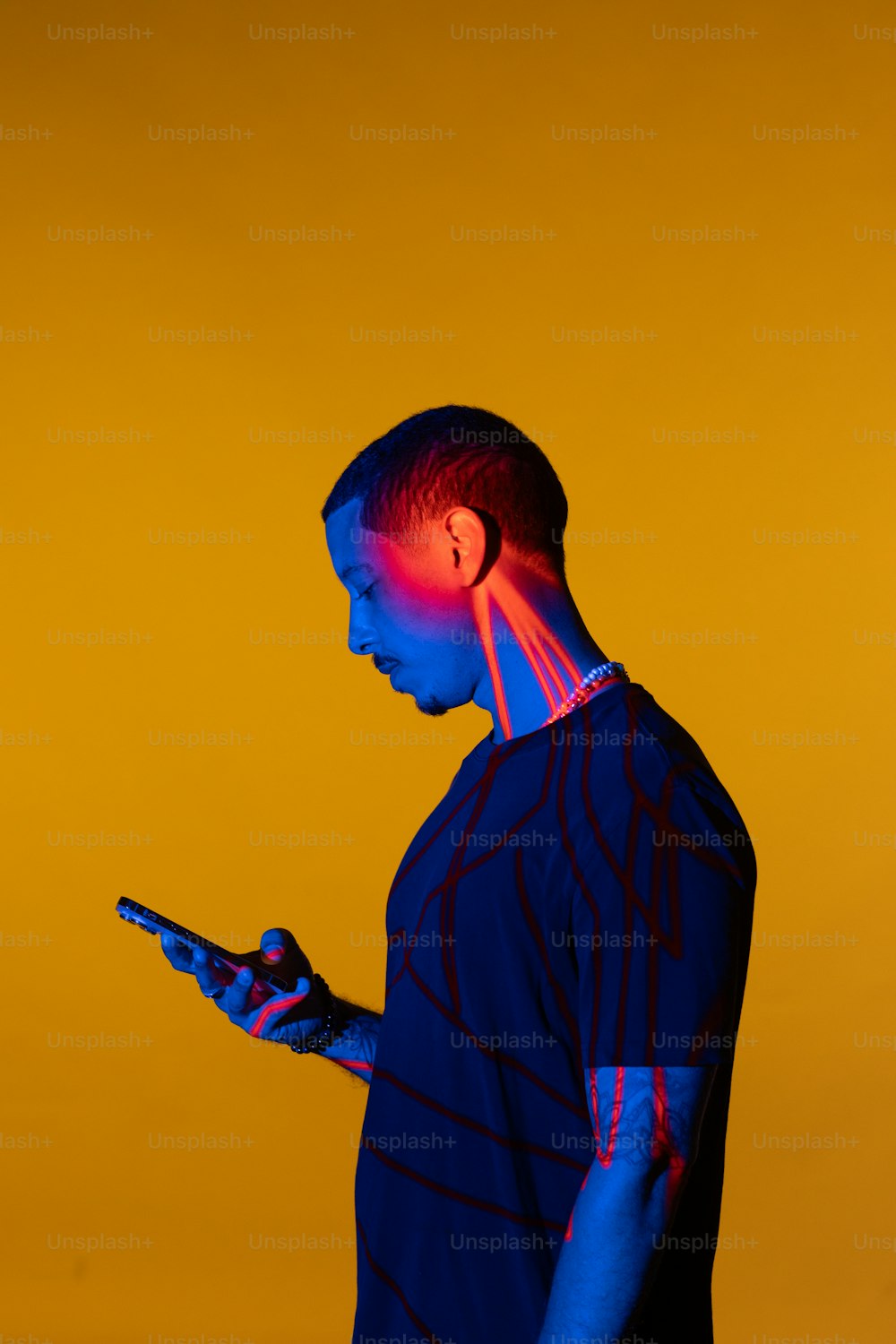 a man standing in front of a yellow background holding a cell phone