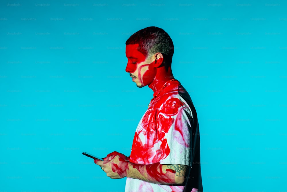 Un hombre con pintura roja en la cara usando un teléfono celular