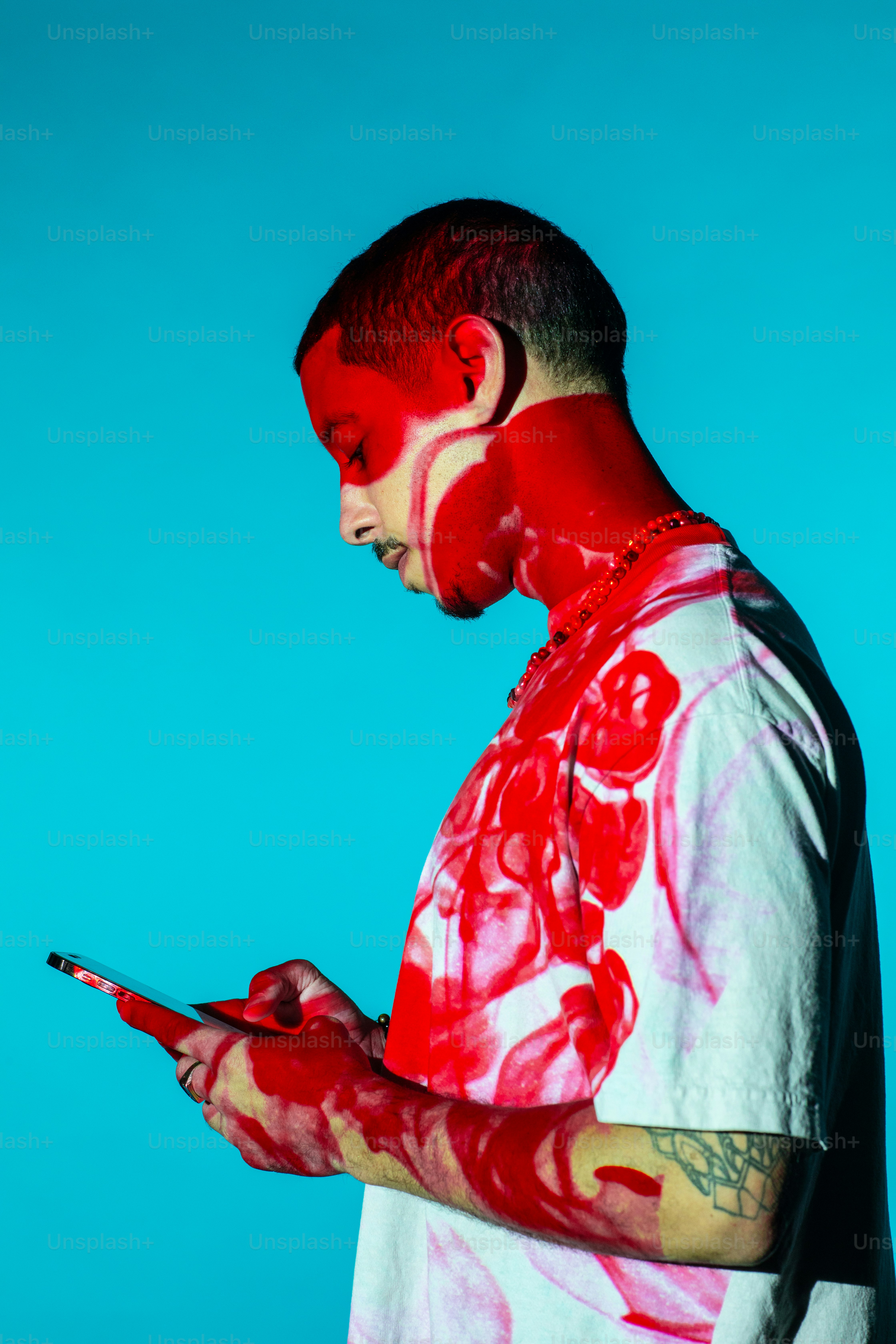 a man with red paint on his face using a cell phone