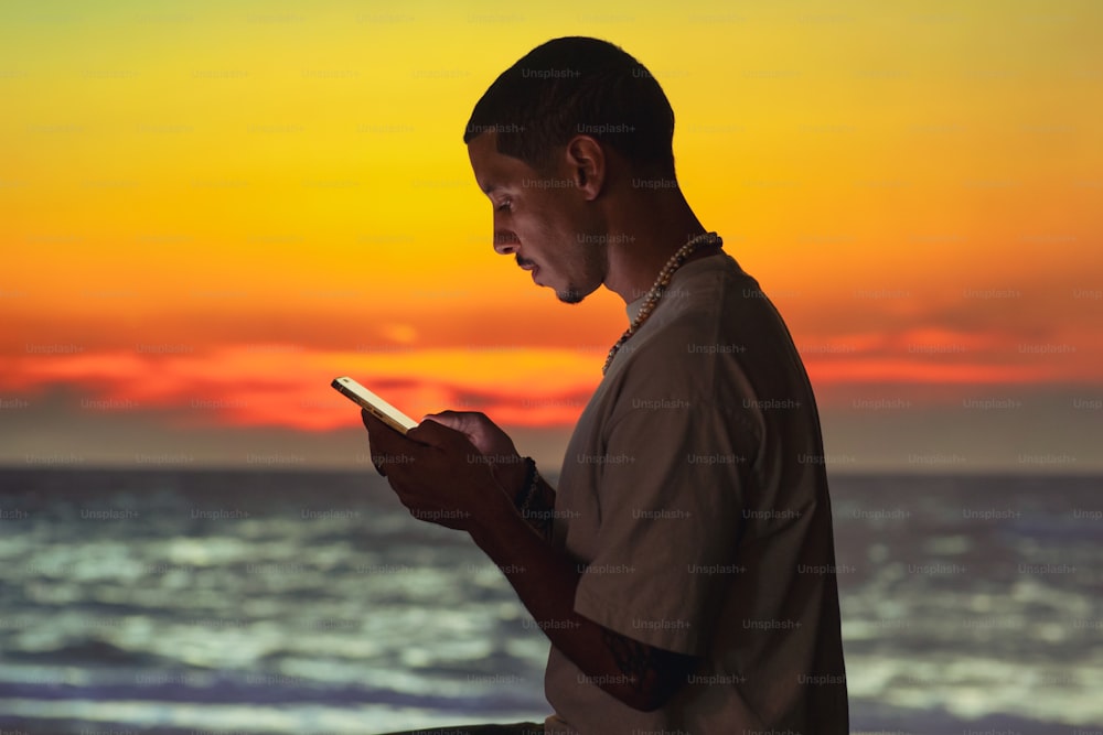 a man sitting on a beach looking at his cell phone