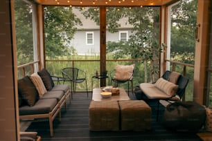un porche couvert avec un canapé, une chaise, un pouf et une table basse