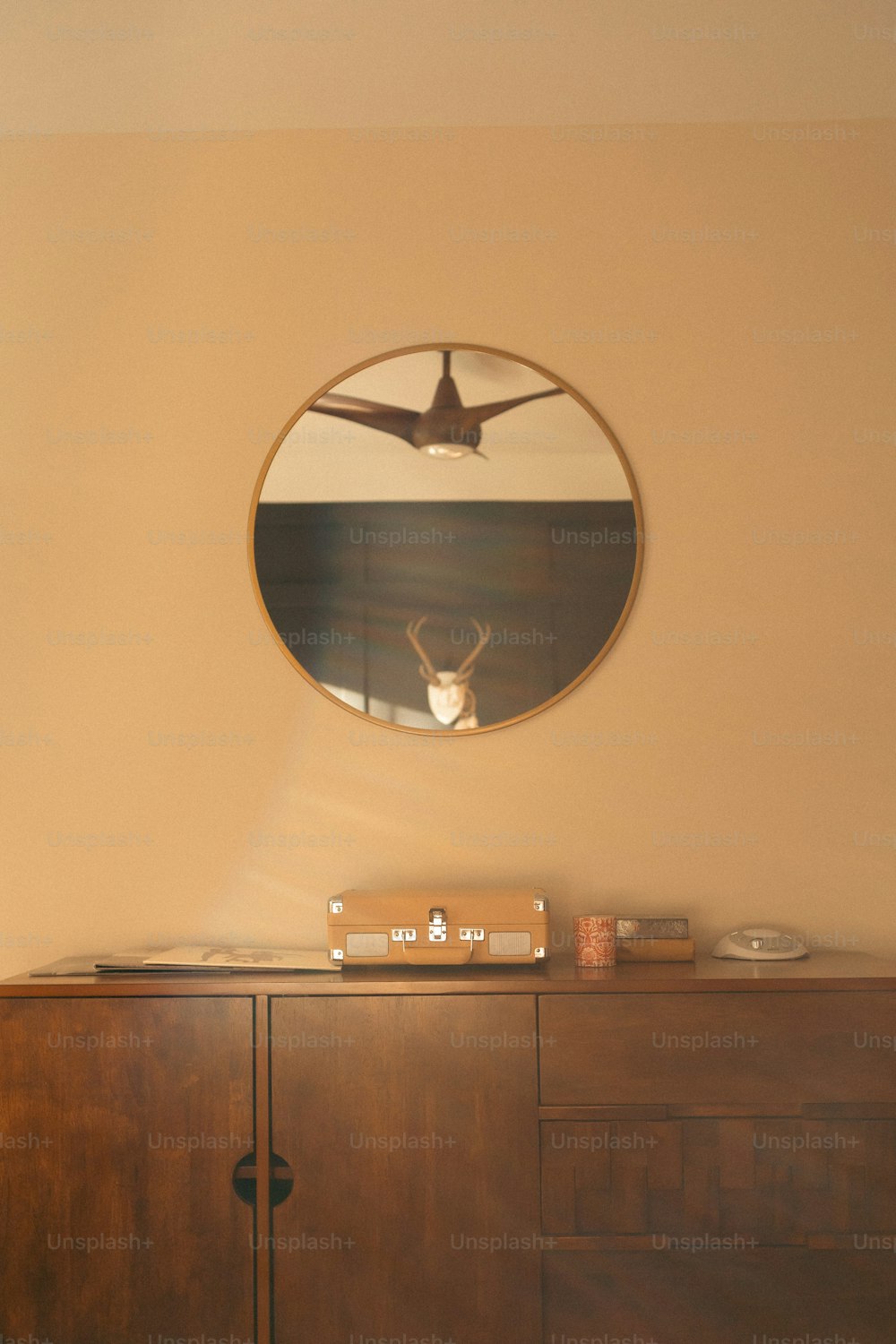 a wooden cabinet with a round mirror above it