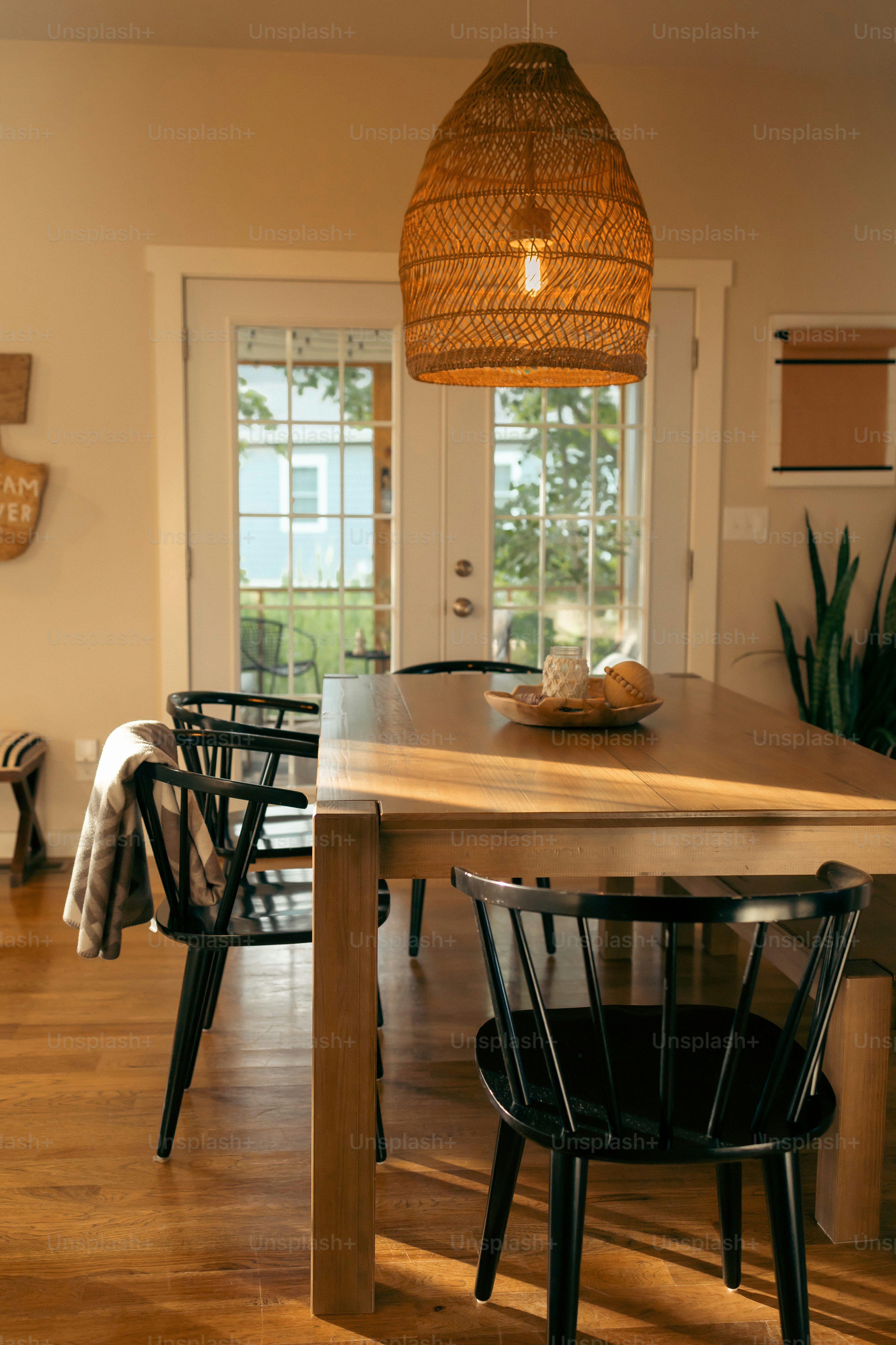 a dining room table with chairs and a basket hanging from the ceiling