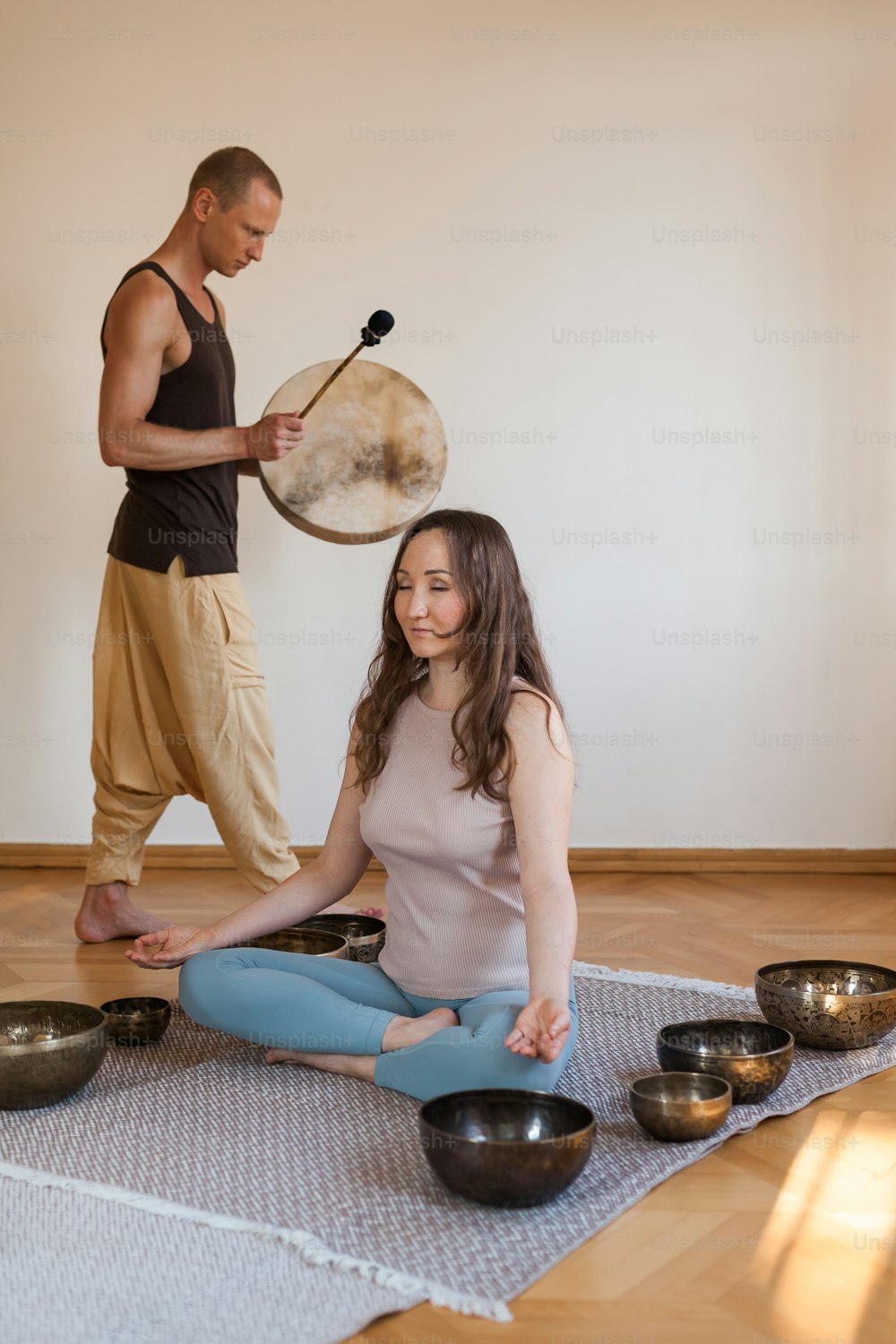 Un hombre y una mujer sentados en el suelo con cuencos y gongs