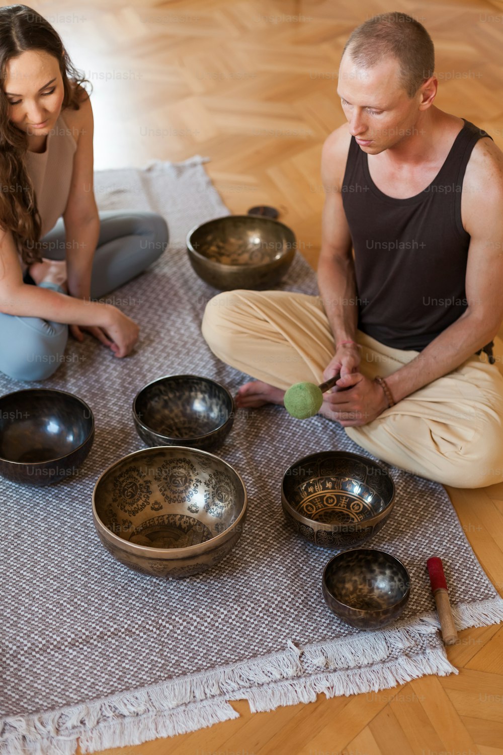 a man and a woman sitting on the floor in front of bowls