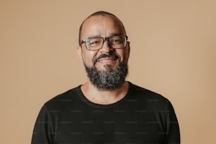 um homem com barba usando óculos e camisa preta
