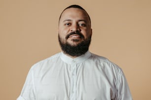 Un homme avec une barbe portant une chemise blanche