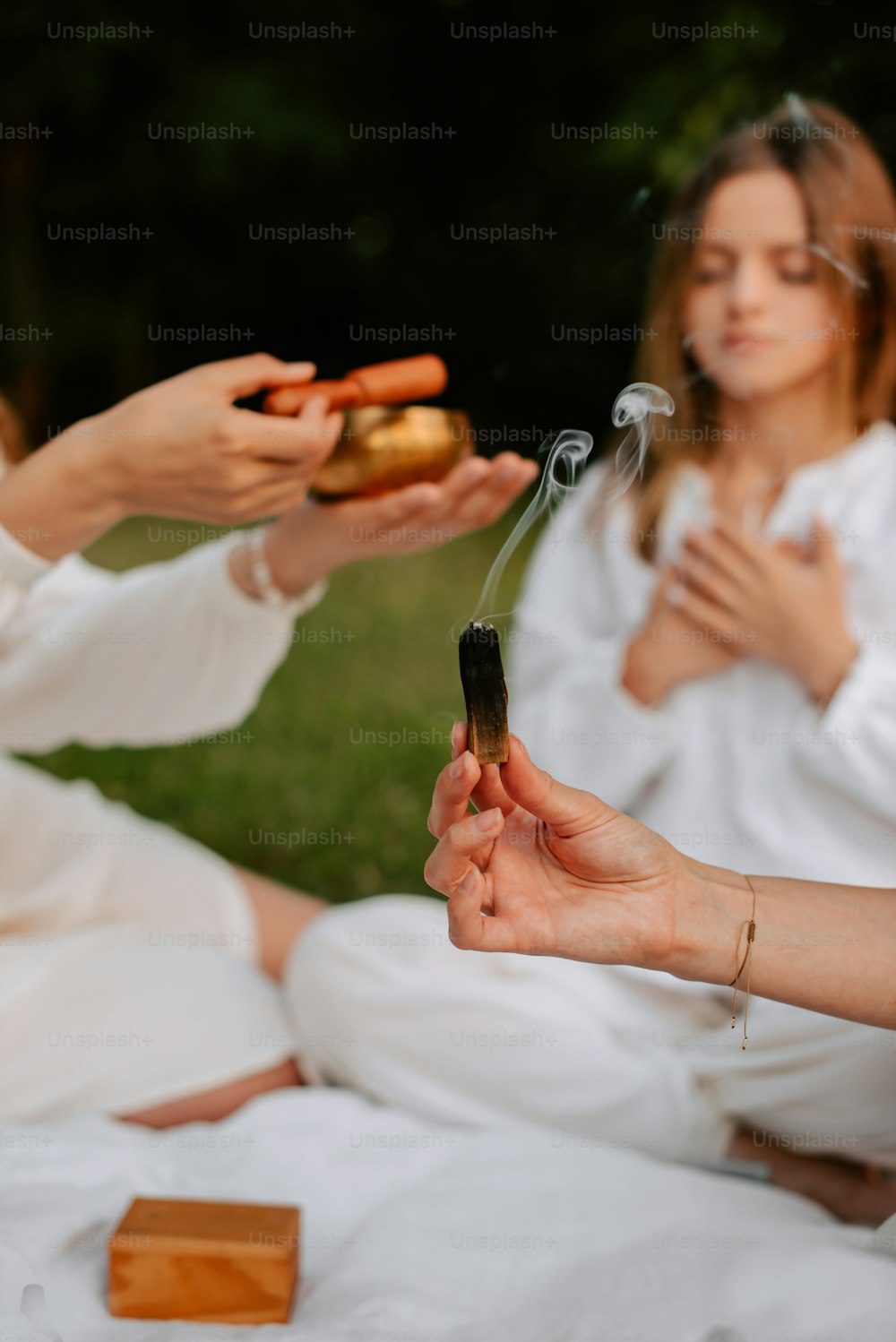 a group of women sitting on top of a grass covered field