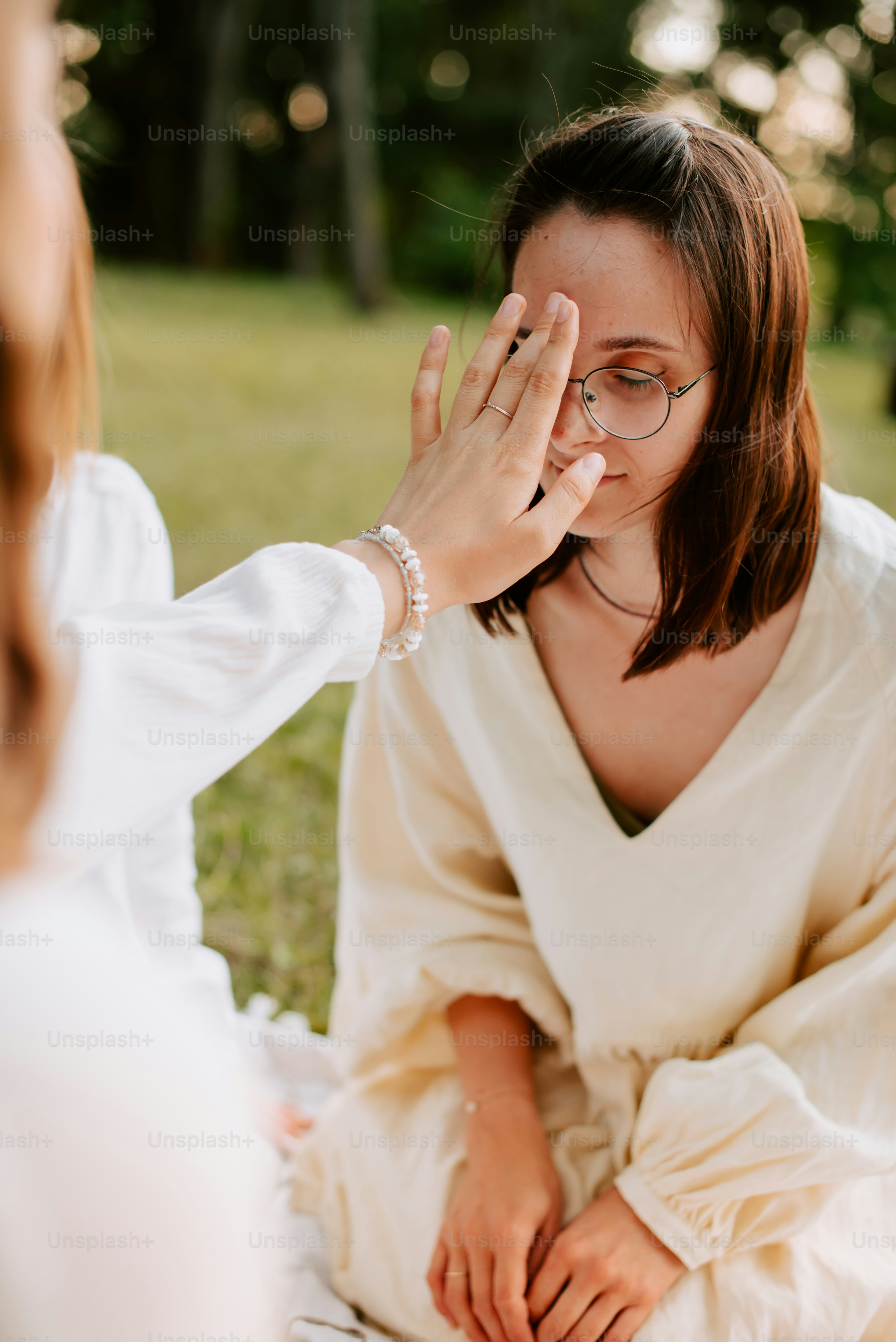 a woman sitting on the ground holding her hand to her face