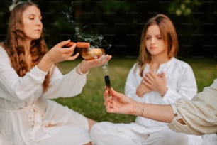 Dos mujeres sentadas en la hierba sosteniendo un cigarrillo y una copa de vino