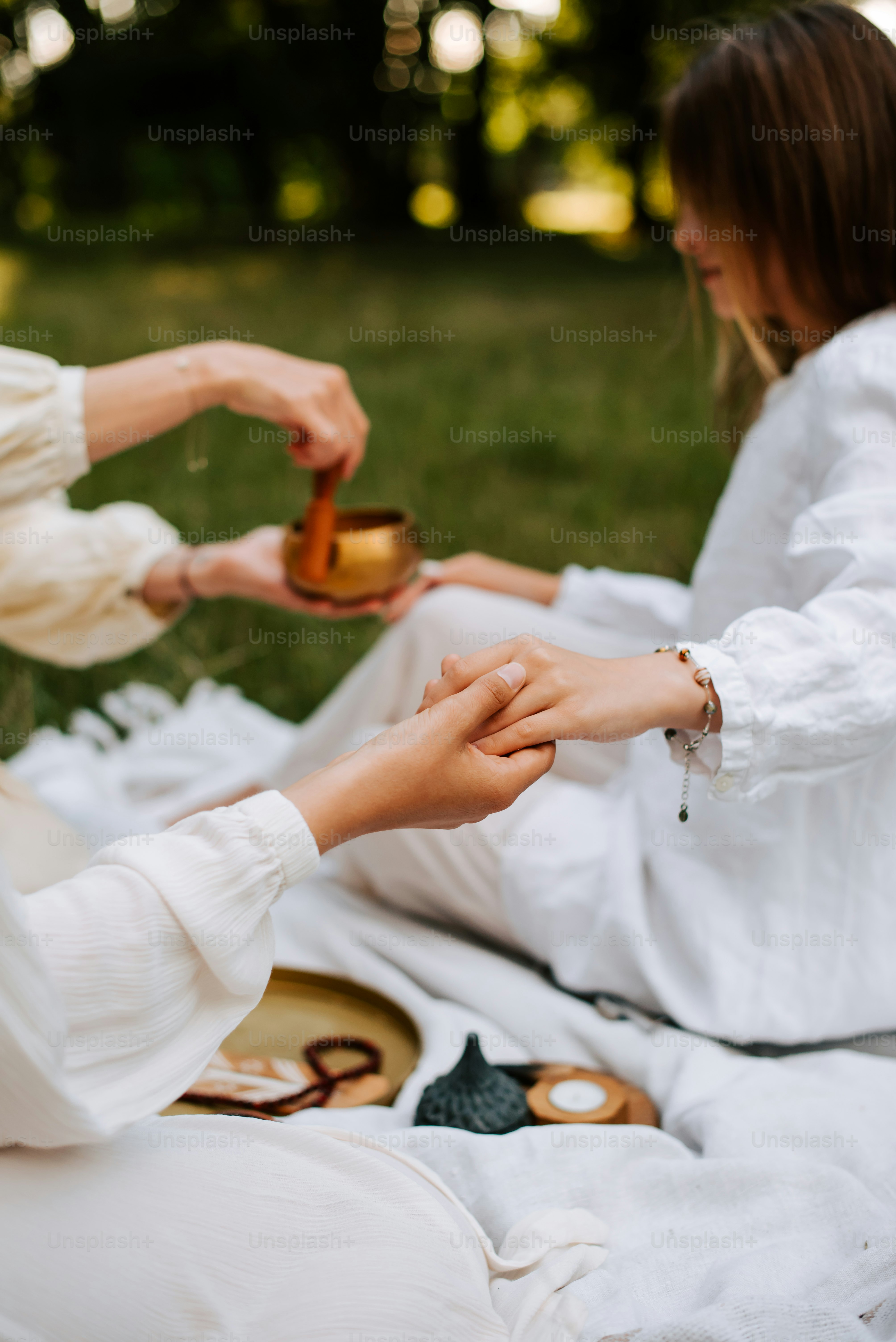 a couple of women sitting on top of a grass covered field