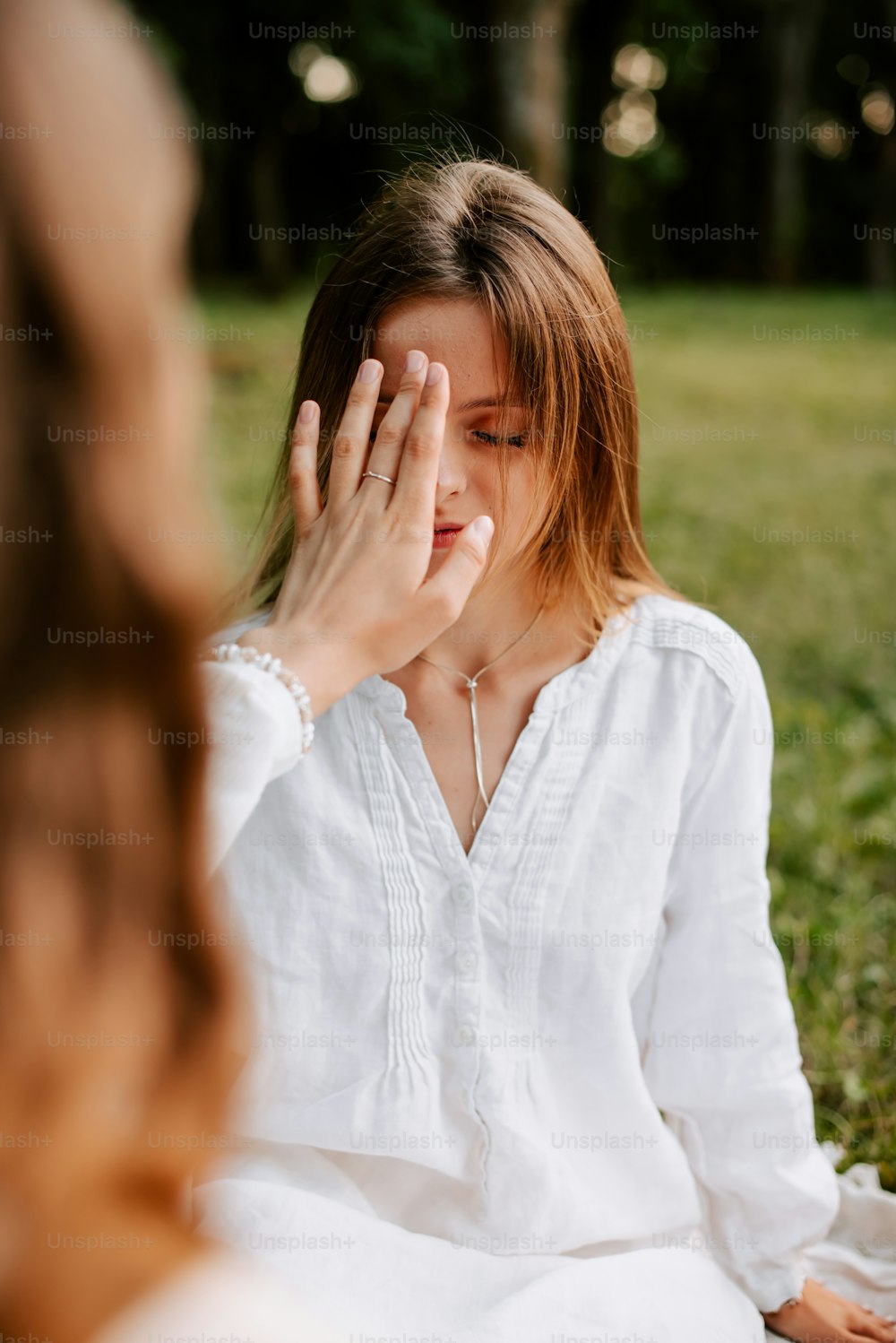 a woman sitting on the ground holding her hand to her face