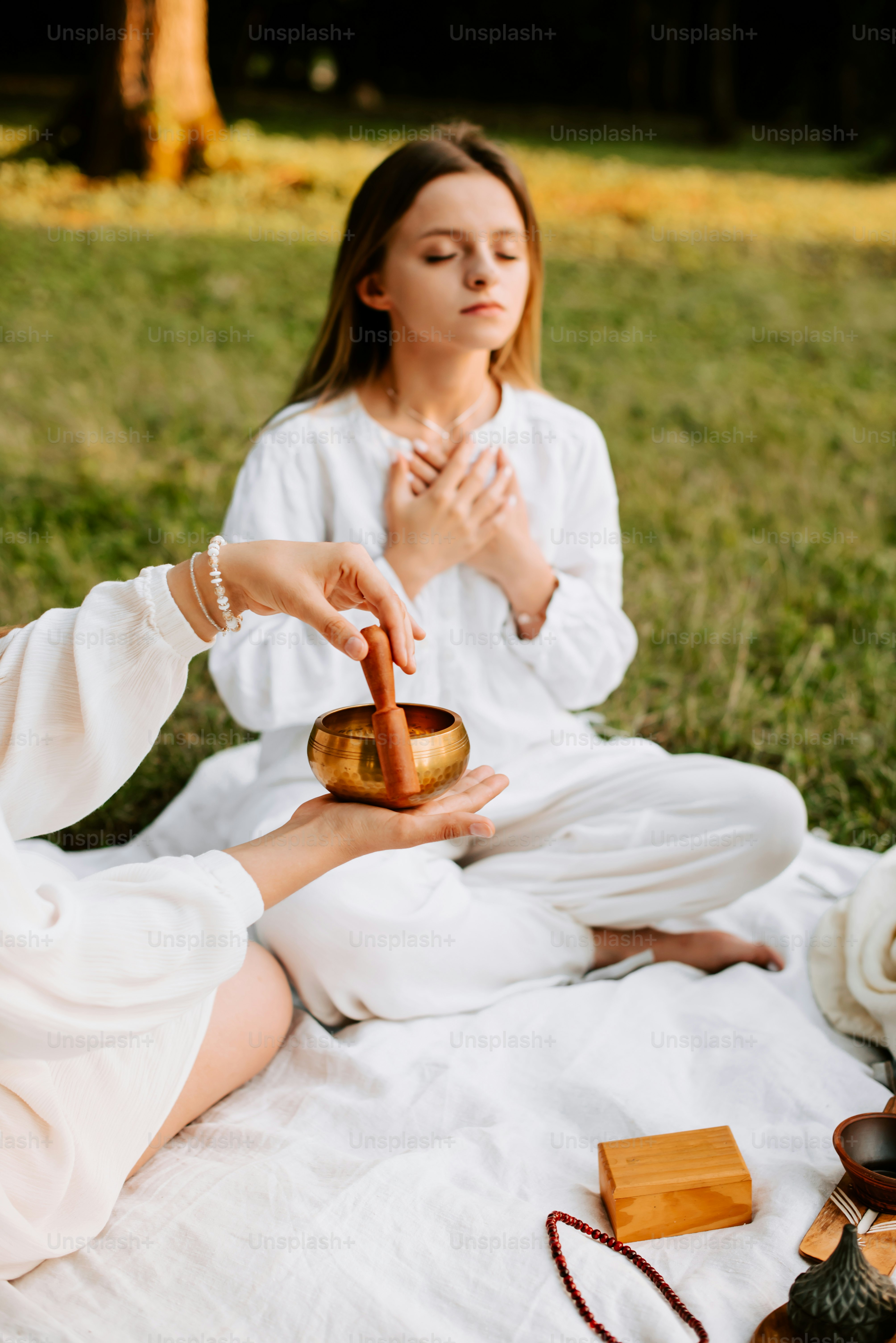 a woman sitting on a blanket holding a bowl