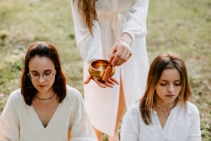 a woman holding a small bowl in front of two other women