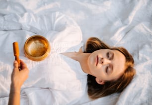 a woman laying in bed with a bowl and a spoon