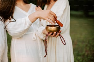 two women in white dresses are holding a candle