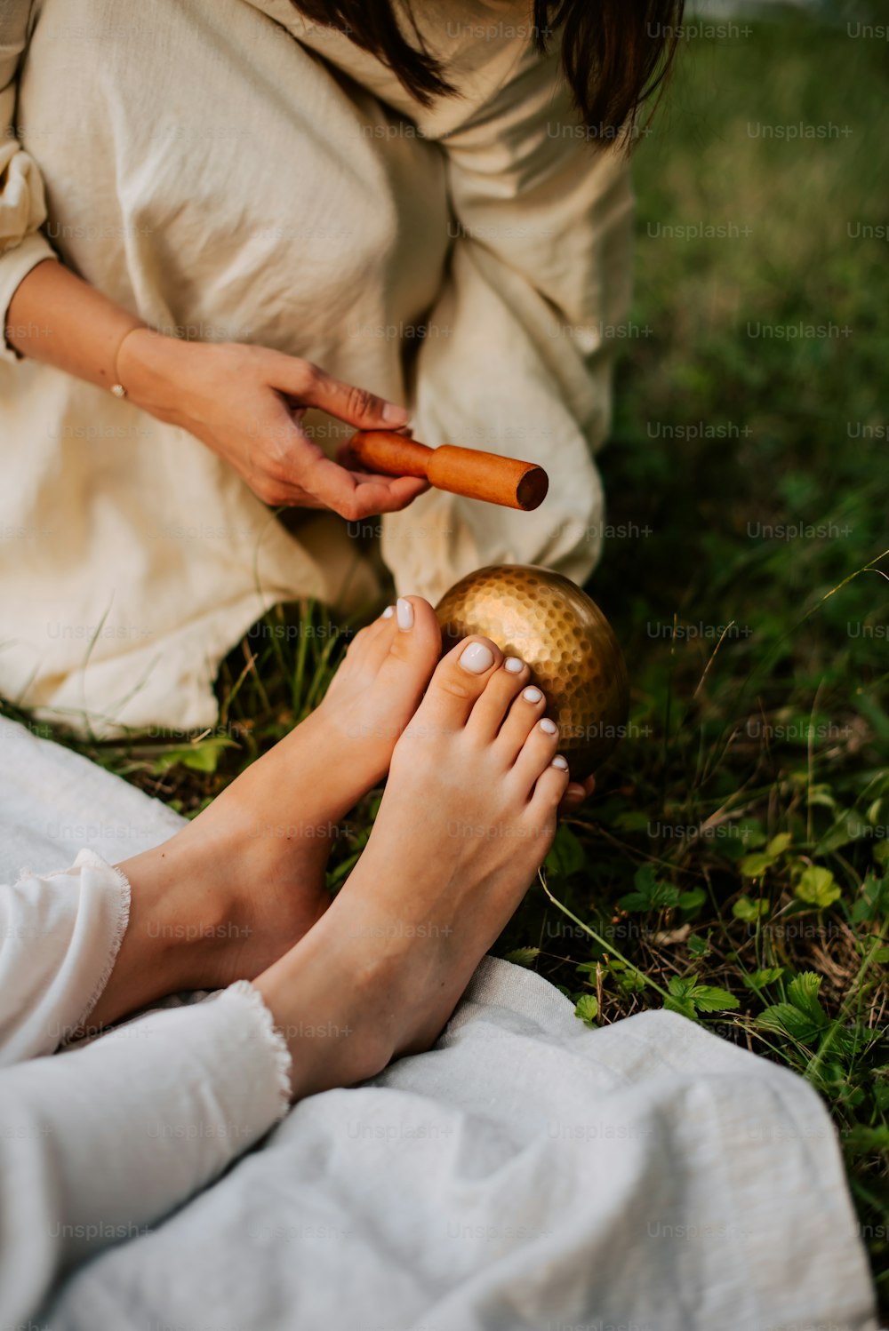 a woman sitting on the ground holding a carrot