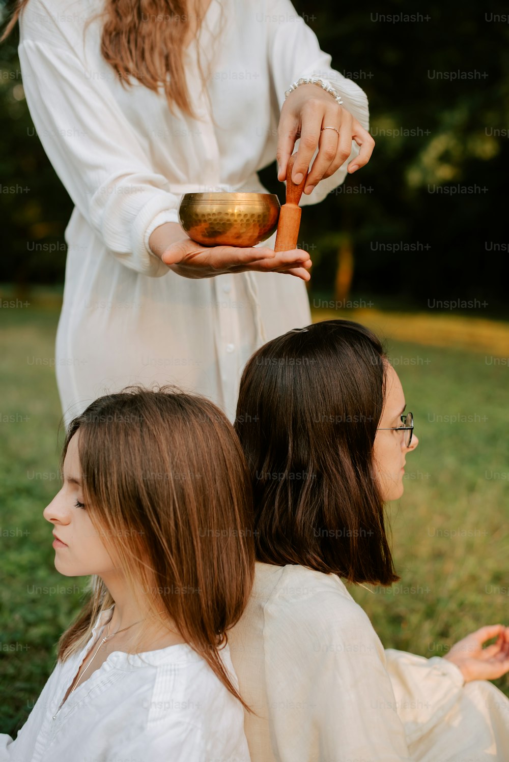 two women sitting in a field one of them is holding a bowl and the other